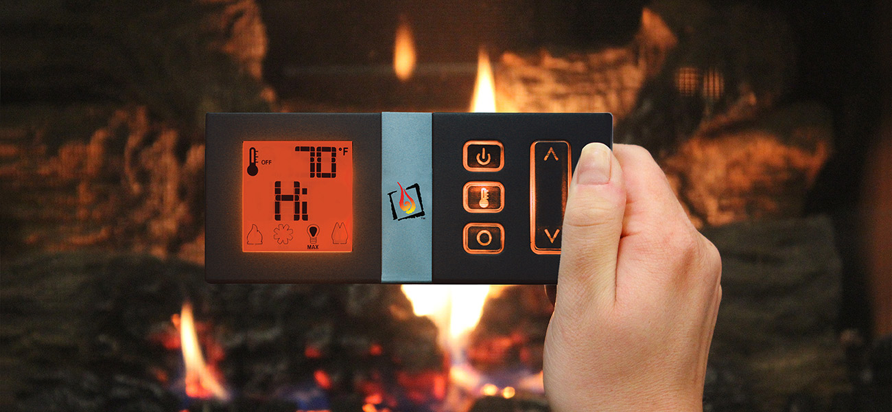 GreenSmart remote held in front of a burning fireplace